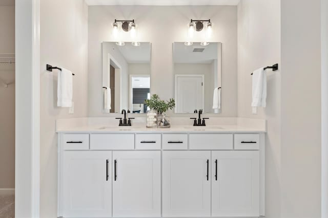 full bath featuring a sink, baseboards, double vanity, and visible vents