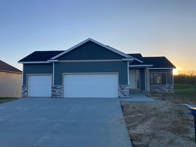 view of front of home featuring stone siding, an attached garage, and driveway
