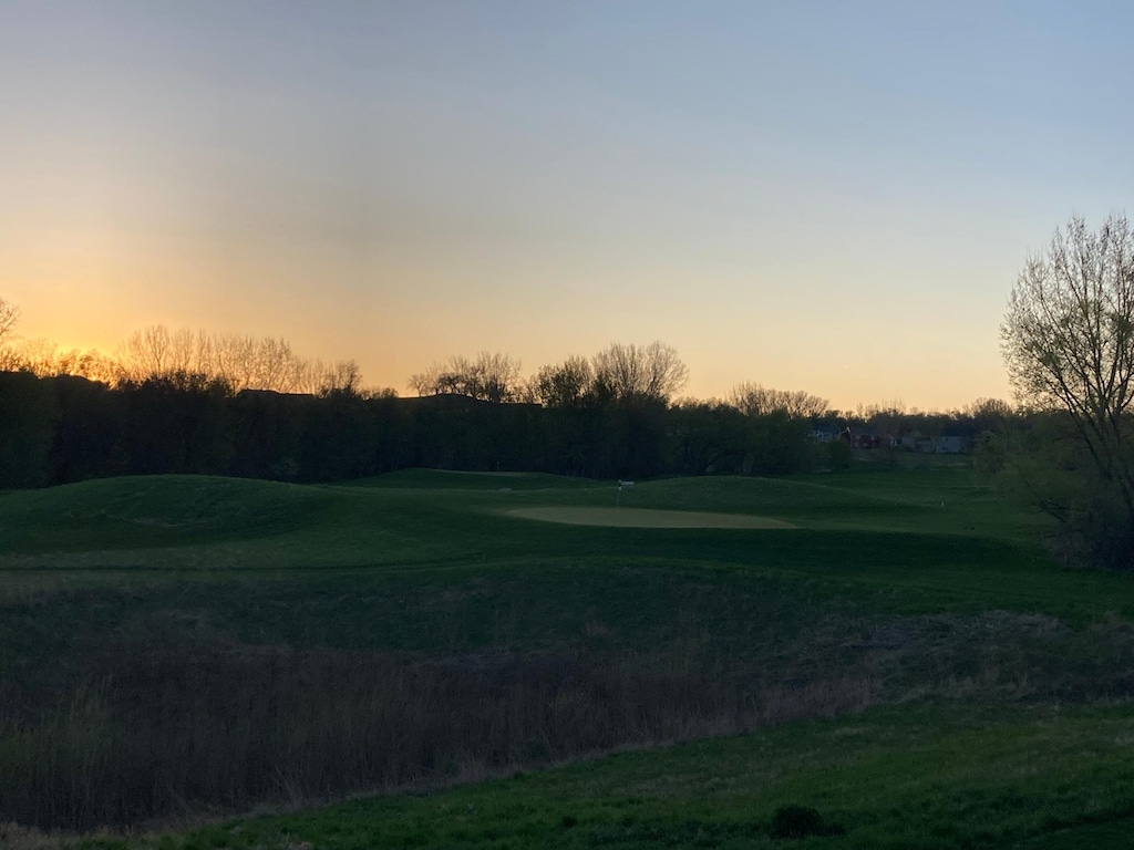 surrounding community with golf course view and a putting area