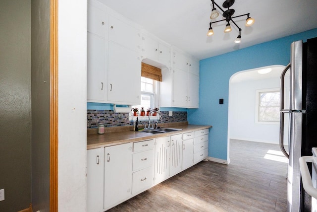 kitchen featuring freestanding refrigerator, a sink, white cabinets, light countertops, and tasteful backsplash
