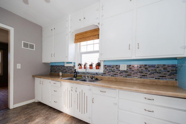 kitchen featuring visible vents, a sink, white cabinetry, wood finished floors, and tasteful backsplash