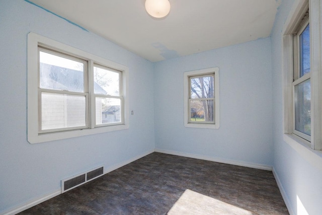 unfurnished room featuring baseboards, visible vents, and wood finished floors