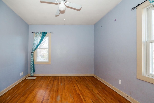 spare room with ceiling fan, a wealth of natural light, baseboards, and wood finished floors
