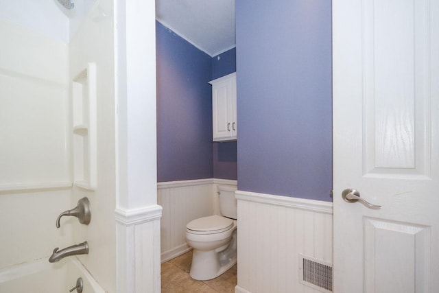 full bath with toilet, shower / washtub combination, a wainscoted wall, visible vents, and tile patterned flooring