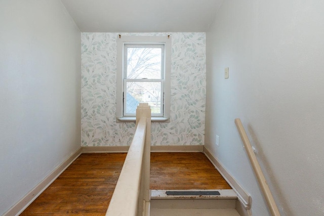 interior space featuring wallpapered walls, wood finished floors, and baseboards