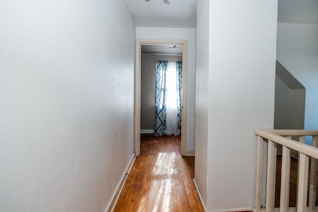 hall with an upstairs landing, light wood-style flooring, and baseboards