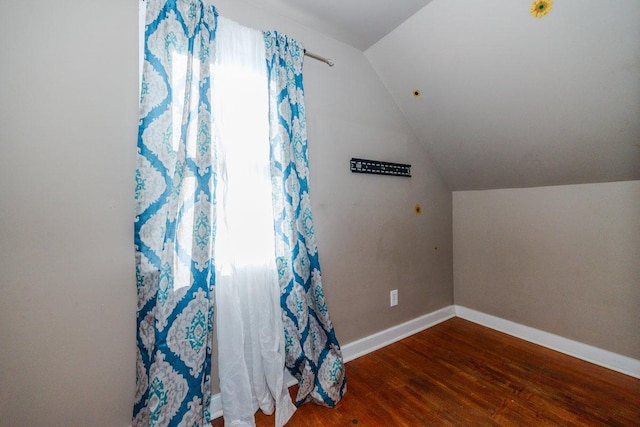 additional living space with baseboards, wood finished floors, and lofted ceiling