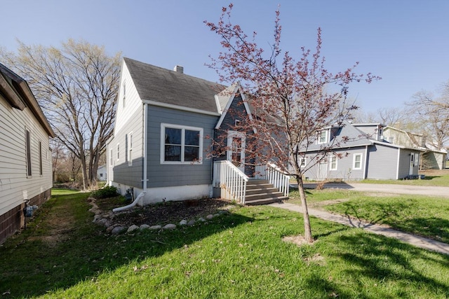 view of front of property with a shingled roof and a front lawn