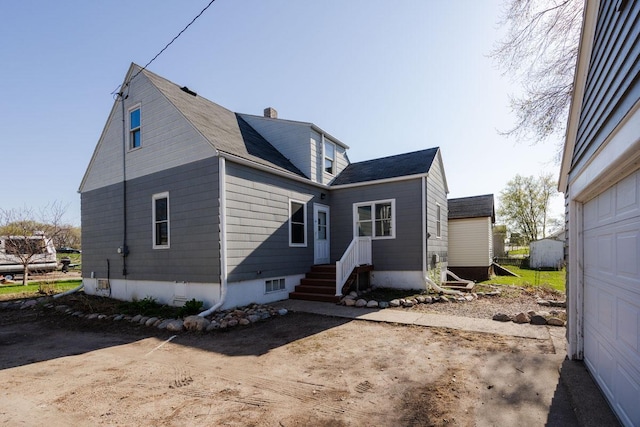 back of property featuring roof with shingles, a garage, a chimney, and driveway