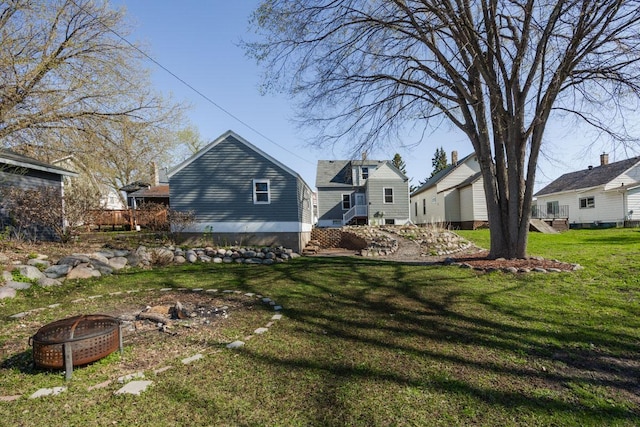 back of property featuring a lawn and a fire pit
