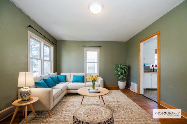 living area with baseboards, a wealth of natural light, and wood finished floors