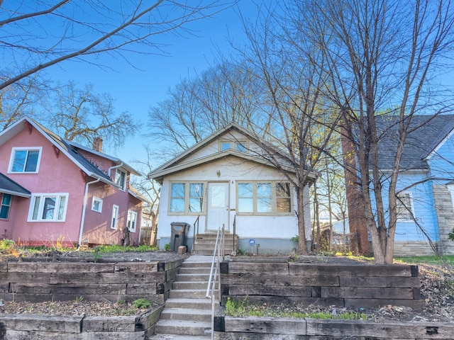 bungalow-style house featuring a chimney and stucco siding