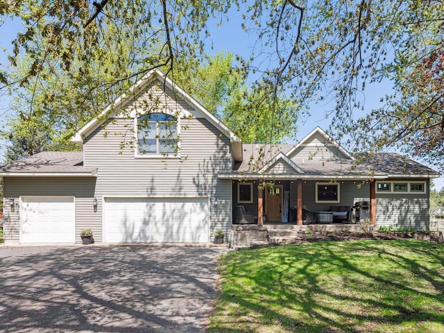 view of front of house with a garage, aphalt driveway, a front yard, a porch, and roof with shingles