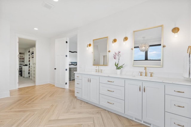 bathroom with a sink, a walk in closet, double vanity, and visible vents