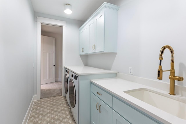 washroom featuring a sink, cabinet space, baseboards, and independent washer and dryer