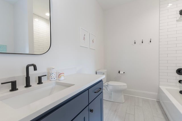 full bath featuring toilet, wood finished floors, bathtub / shower combination, baseboards, and vanity