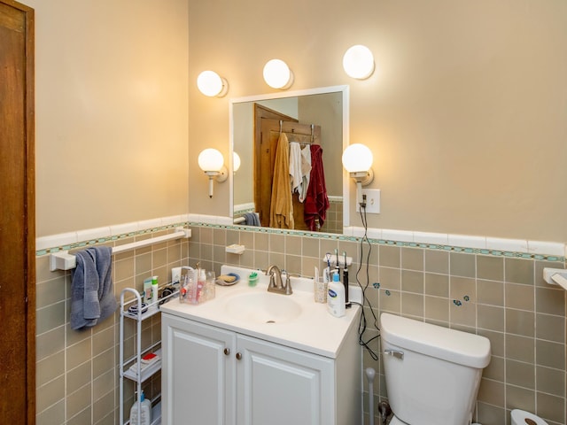 bathroom featuring a wainscoted wall, toilet, tile walls, and vanity