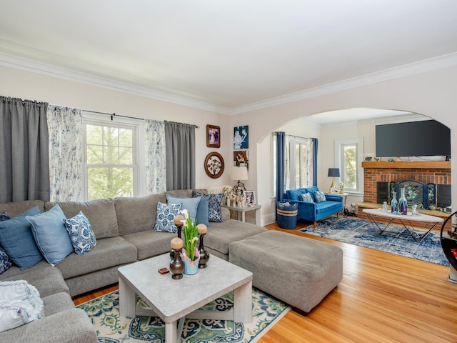 living area with arched walkways, healthy amount of natural light, wood finished floors, and crown molding