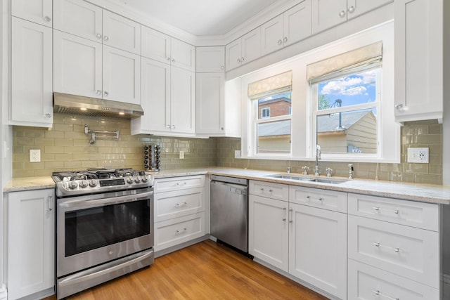 1520 Randolph Ave, Saint Paul, MN 55105 - kitchen featuring appliances with stainless steel finishes, under cabinet range hood, a sink, decorative backsplash, and white cabinetry