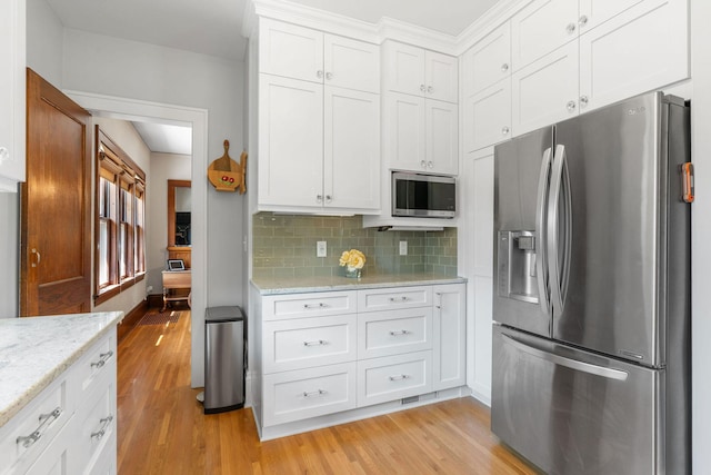 1520 Randolph Ave, Saint Paul, MN 55105 - kitchen with appliances with stainless steel finishes, light wood-style flooring, white cabinetry, decorative backsplash, and light stone countertops