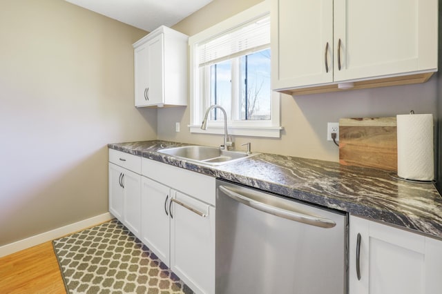 kitchen with a sink, light wood-style flooring, white cabinets, stainless steel dishwasher, and baseboards