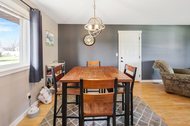 dining space featuring a notable chandelier, baseboards, and wood finished floors