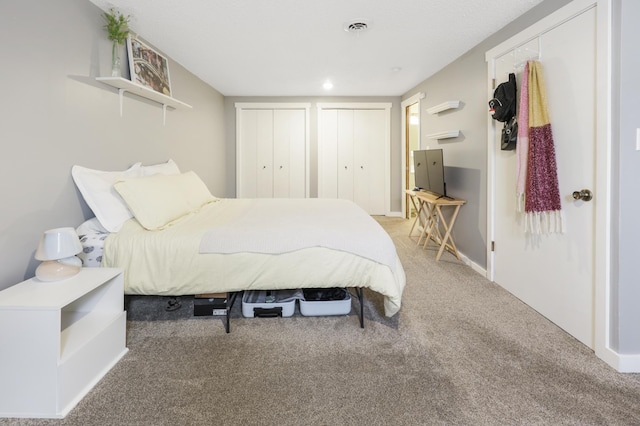 carpeted bedroom with visible vents, baseboards, and multiple closets