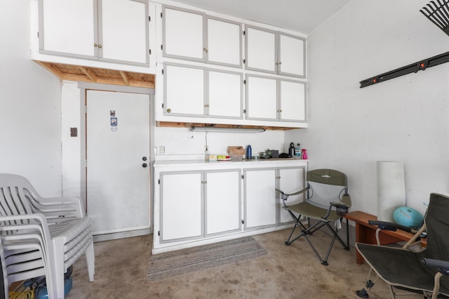 interior space with light countertops, white cabinets, and unfinished concrete flooring