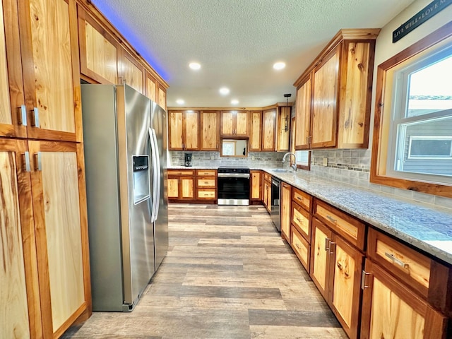 kitchen featuring stainless steel appliances, light wood-style flooring, decorative backsplash, light stone countertops, and recessed lighting