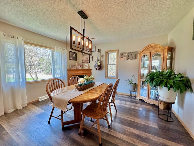 dining space featuring a textured ceiling, dark wood finished floors, a chandelier, and baseboards