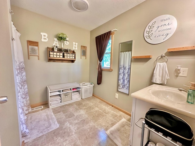 bathroom with baseboards, vanity, and stone finish floors