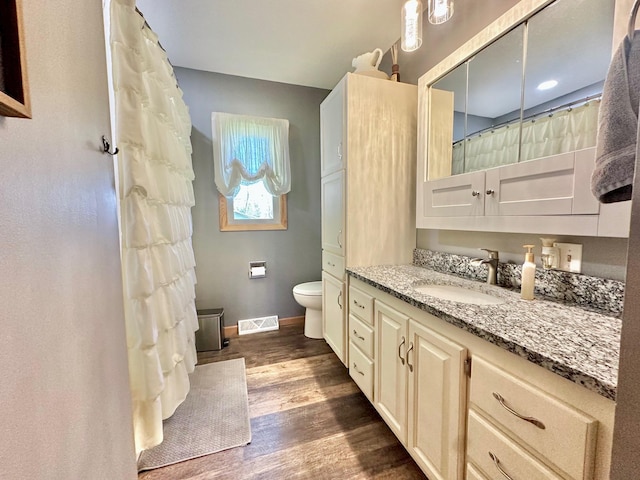bathroom featuring toilet, vanity, wood finished floors, baseboards, and a shower with shower curtain