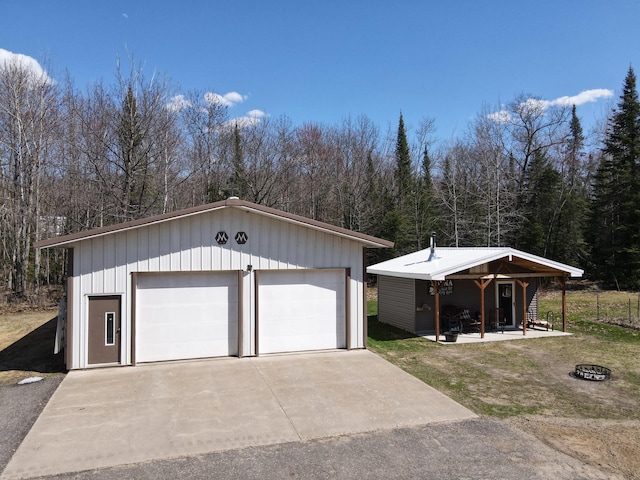 view of front of house featuring an outdoor structure, a garage, a forest view, and board and batten siding