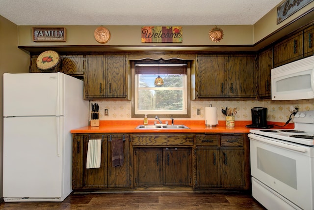 kitchen featuring a sink, white appliances, light countertops, and dark wood finished floors