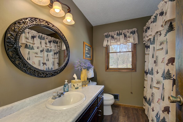 full bathroom with toilet, wood finished floors, vanity, a textured ceiling, and visible vents