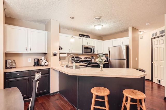 2492 Yellowstone Dr Unit 82, Hastings, MN 55033 - kitchen featuring stainless steel appliances, a sink, dark wood-style flooring, a breakfast bar area, and a textured ceiling