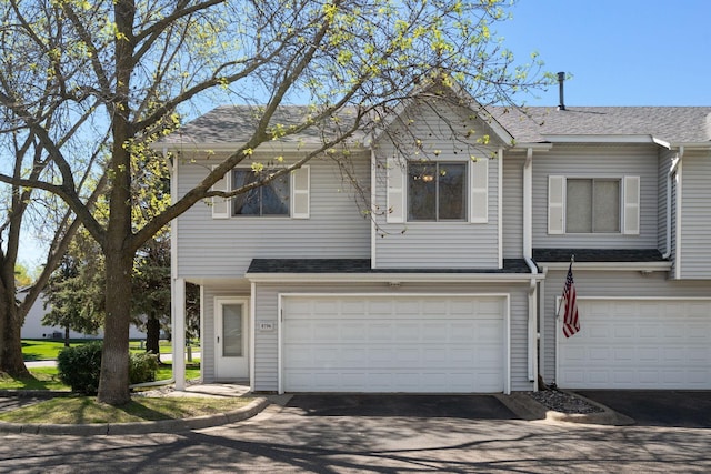 view of front of home with driveway, an attached garage, and roof with shingles