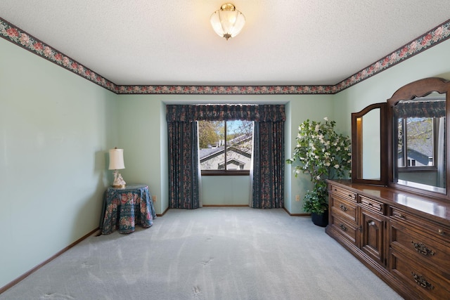 bedroom featuring light colored carpet, baseboards, and a textured ceiling