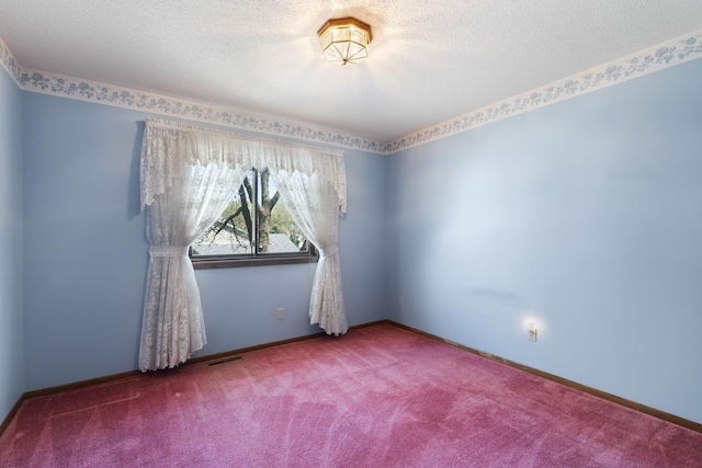 carpeted empty room featuring a textured ceiling and baseboards