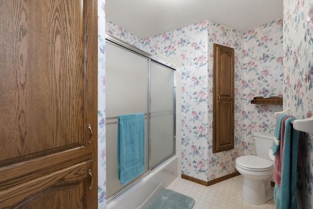 full bathroom with wallpapered walls, bath / shower combo with glass door, toilet, baseboards, and a textured ceiling