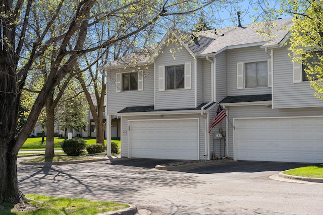 view of front of house with an attached garage, driveway, and roof with shingles