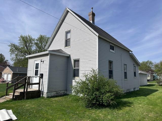 609 13th St NE, Austin, MN 55912 - view of side of property featuring a lawn and a chimney