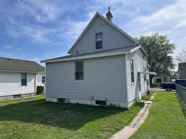 609 13th St NE, Austin, MN 55912 - view of property exterior featuring a chimney and a yard