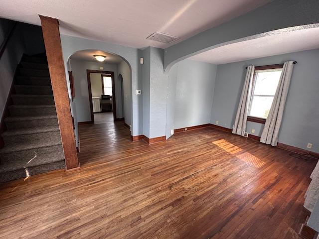 609 13th St NE, Austin, MN 55912 - empty room with arched walkways, wood finished floors, healthy amount of natural light, and stairs