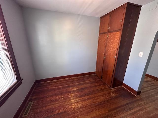 609 13th St NE, Austin, MN 55912 - unfurnished bedroom featuring dark wood-style flooring, baseboards, and a closet