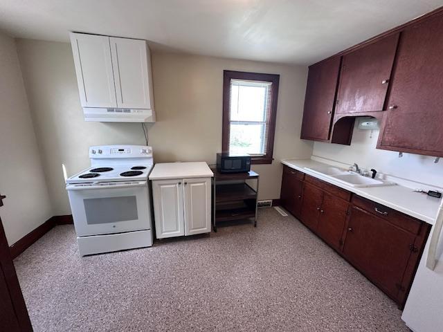 609 13th St NE, Austin, MN 55912 - kitchen featuring white electric stove, light countertops, white cabinets, and baseboards