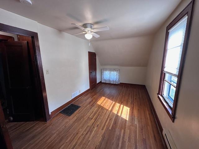 609 13th St NE, Austin, MN 55912 - additional living space featuring healthy amount of natural light, dark wood finished floors, ceiling fan, vaulted ceiling, and a baseboard radiator