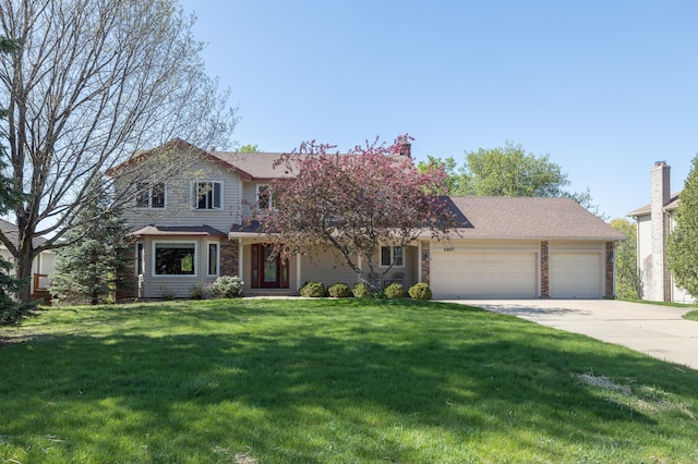 traditional-style home featuring an attached garage, concrete driveway, and a front yard