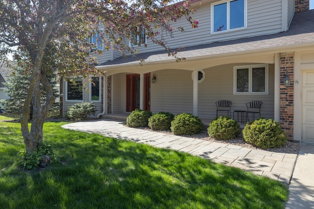 view of front of property with a front lawn, brick siding, and a shingled roof