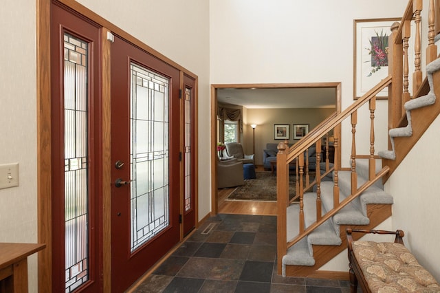 foyer entrance with stairs, a high ceiling, and baseboards